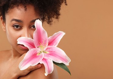 Photo of Portrait of beautiful Brazilian woman with lily flower after spa treatment on light brown background, closeup. Space for text