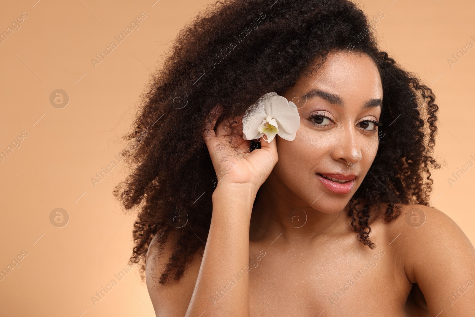Photo of Portrait of beautiful Brazilian woman with orchid flower after spa treatment on beige background