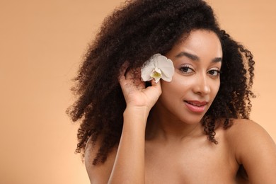 Photo of Portrait of beautiful Brazilian woman with orchid flower after spa treatment on beige background