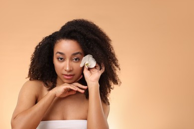 Photo of Portrait of beautiful Brazilian woman with orchid flower after spa treatment on beige gradient background. Space for text