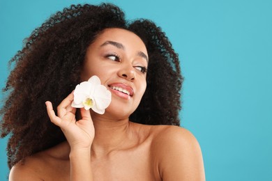 Photo of Portrait of beautiful Brazilian woman with orchid flower after spa treatment on light blue background