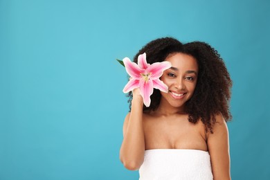 Photo of Portrait of beautiful Brazilian woman with lily flower after spa treatment on light blue background. Space for text