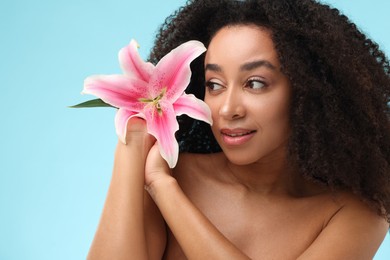 Photo of Portrait of beautiful Brazilian woman with lily flower after spa treatment on light blue background, closeup