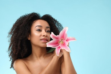 Photo of Portrait of beautiful Brazilian woman with lily flower after spa treatment on light blue background. Space for text