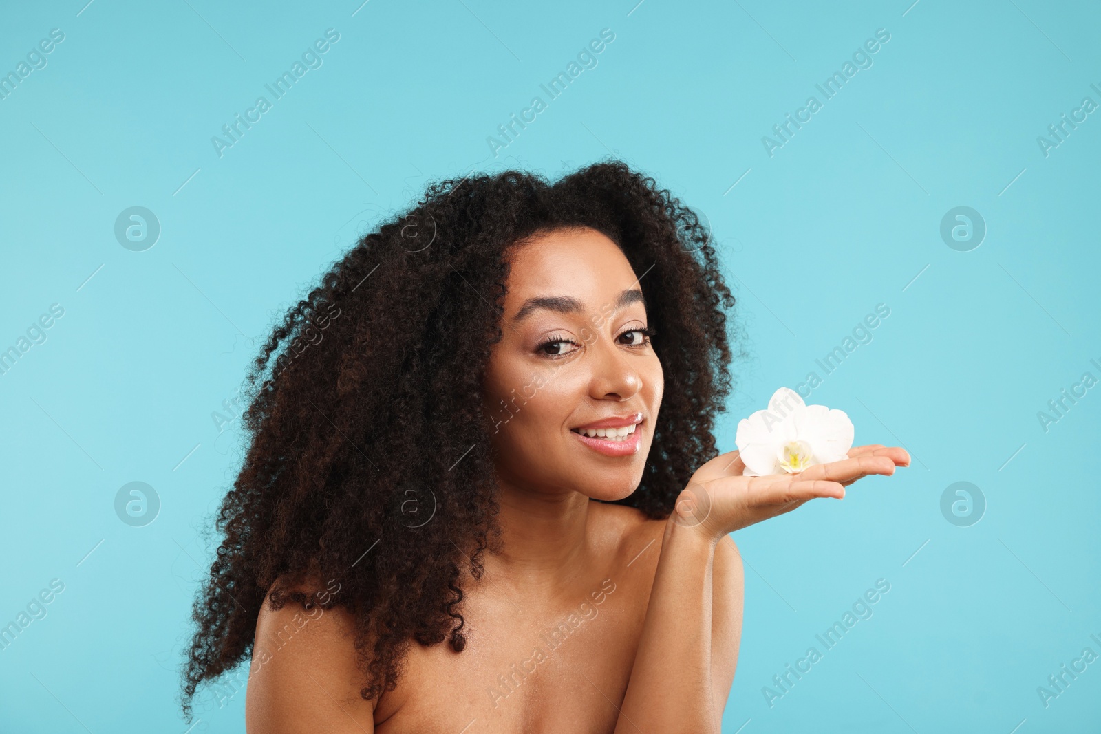 Photo of Portrait of beautiful Brazilian woman with orchid flower after spa treatment on light blue background