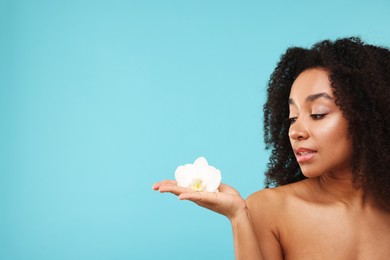 Photo of Portrait of beautiful Brazilian woman with orchid flower after spa treatment on light blue background. Space for text