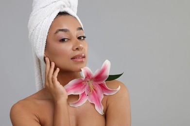 Photo of Portrait of beautiful Brazilian woman with lily flower after spa treatment on gray background. Space for text