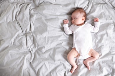 Photo of Cute newborn baby sleeping on bed, top view. Space for text