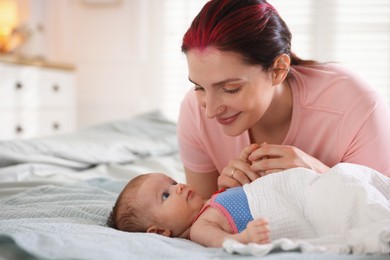 Photo of Mother putting her cute newborn baby to sleep on bed at home