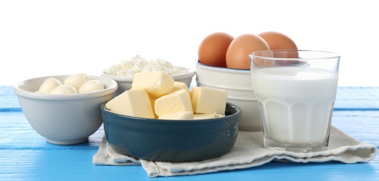 Photo of Different dairy products and eggs on blue wooden table against white background
