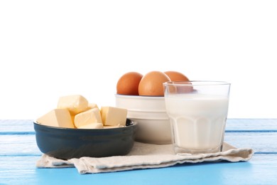 Photo of Milk, butter and eggs on blue wooden table against white background