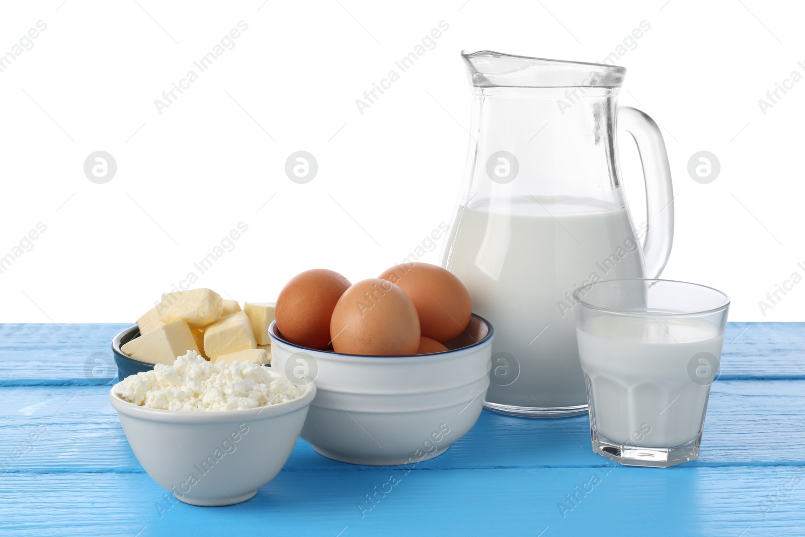 Photo of Different dairy products and eggs on blue wooden table against white background