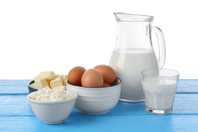 Photo of Different dairy products and eggs on blue wooden table against white background