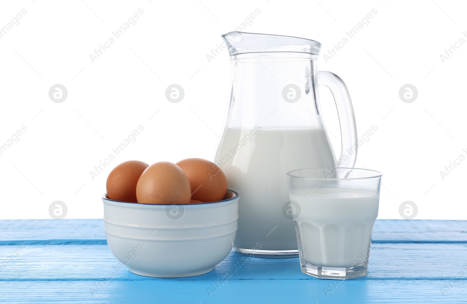 Photo of Milk and eggs on blue wooden table against white background