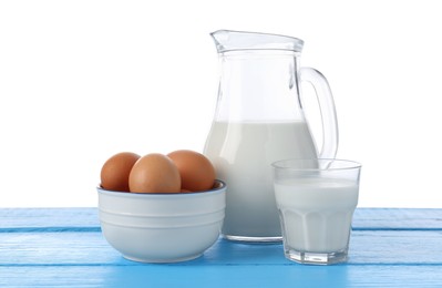 Photo of Milk and eggs on blue wooden table against white background