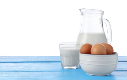 Photo of Milk and eggs on blue wooden table against white background