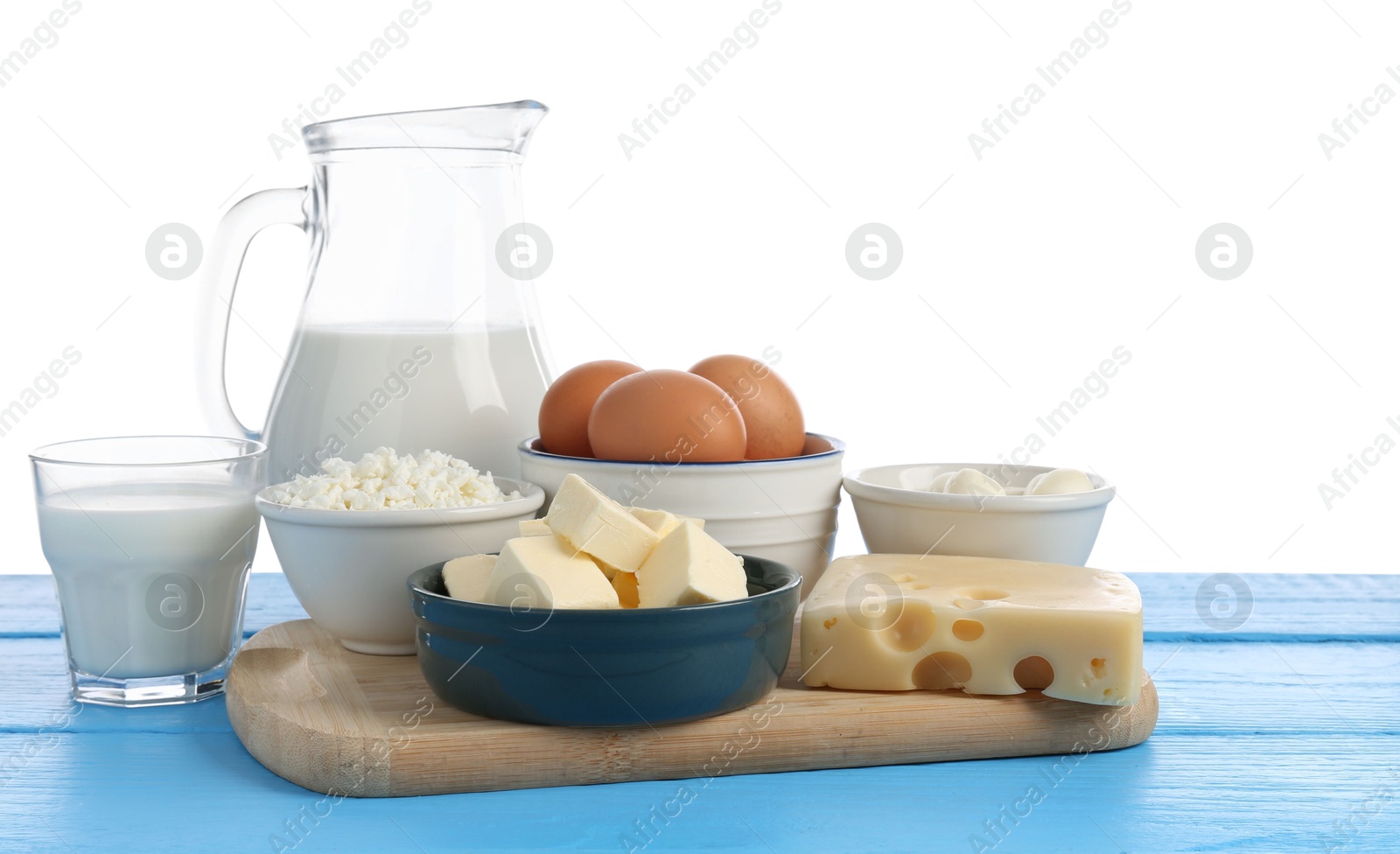 Photo of Different dairy products and eggs on blue wooden table against white background