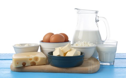Photo of Different dairy products and eggs on blue wooden table against white background