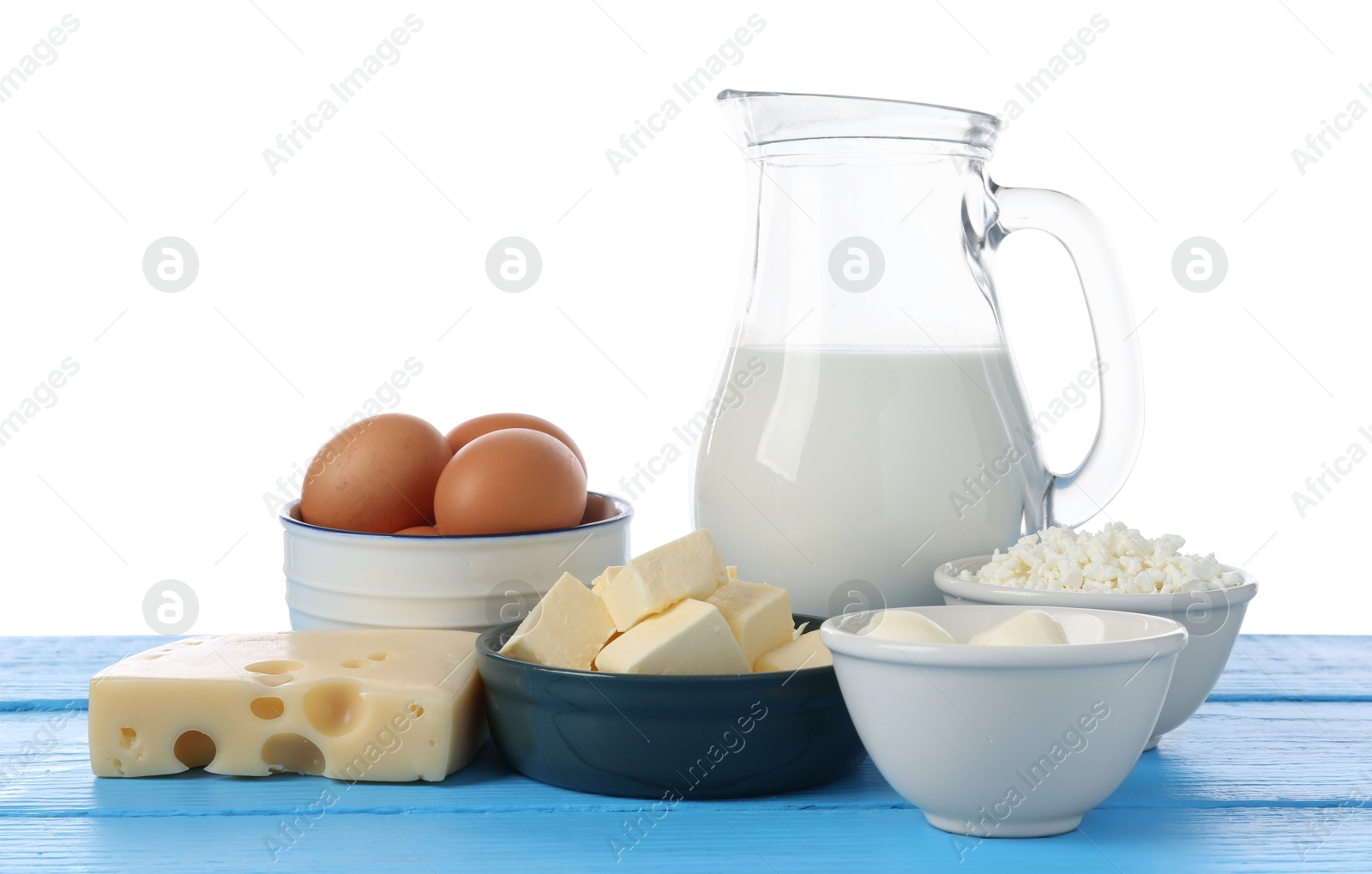 Different dairy products and eggs on blue wooden table against white background Photo of Different dairy products and eggs on blue wooden table against white background