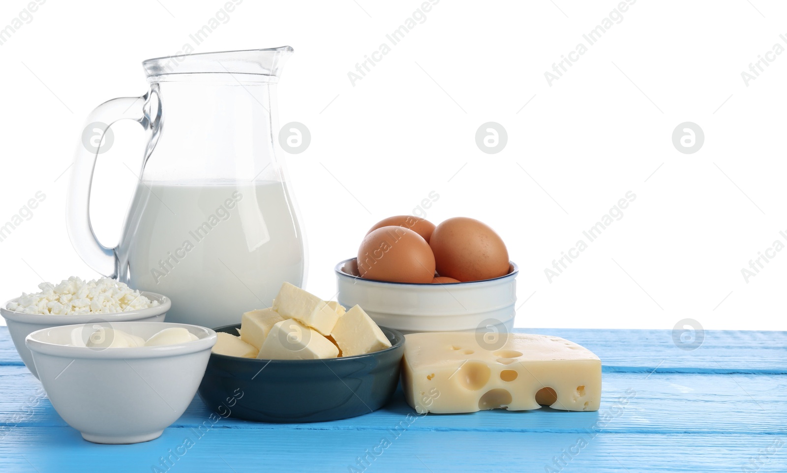 Photo of Different dairy products and eggs on blue wooden table against white background