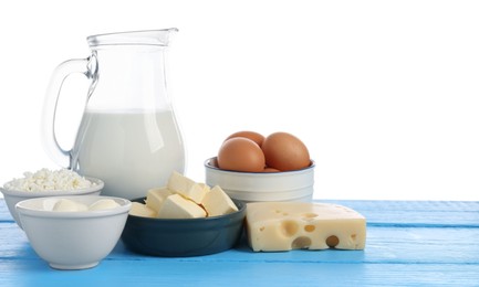 Photo of Different dairy products and eggs on blue wooden table against white background