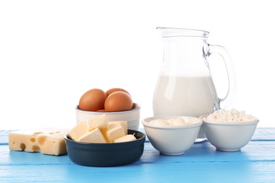 Photo of Different dairy products and eggs on blue wooden table against white background