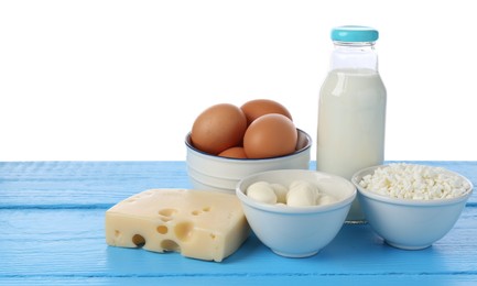 Photo of Different dairy products and eggs on blue wooden table against white background