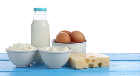 Photo of Different dairy products and eggs on blue wooden table against white background