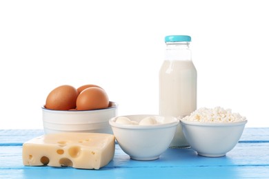 Photo of Different dairy products and eggs on blue wooden table against white background