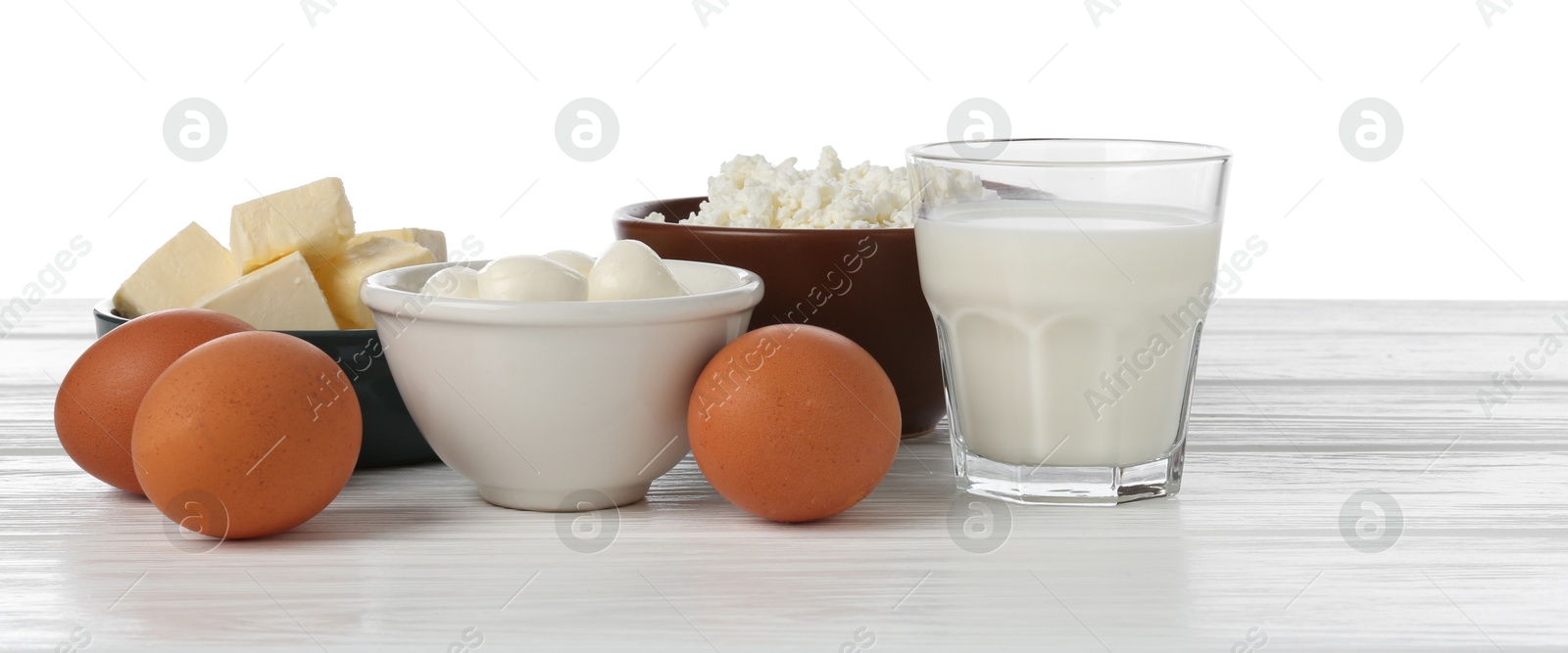 Different dairy products and eggs on wooden table against white background Photo of Different dairy products and eggs on wooden table against white background