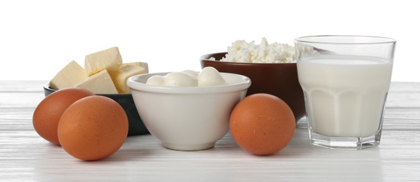 Photo of Different dairy products and eggs on wooden table against white background