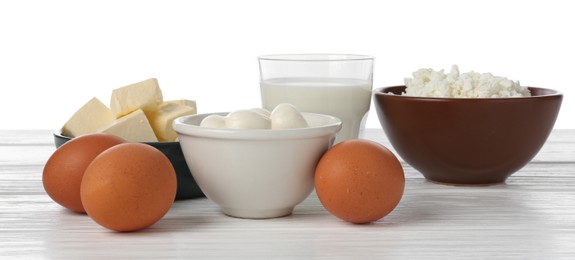Photo of Different dairy products and eggs on wooden table against white background