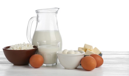 Photo of Different dairy products and eggs on wooden table against white background