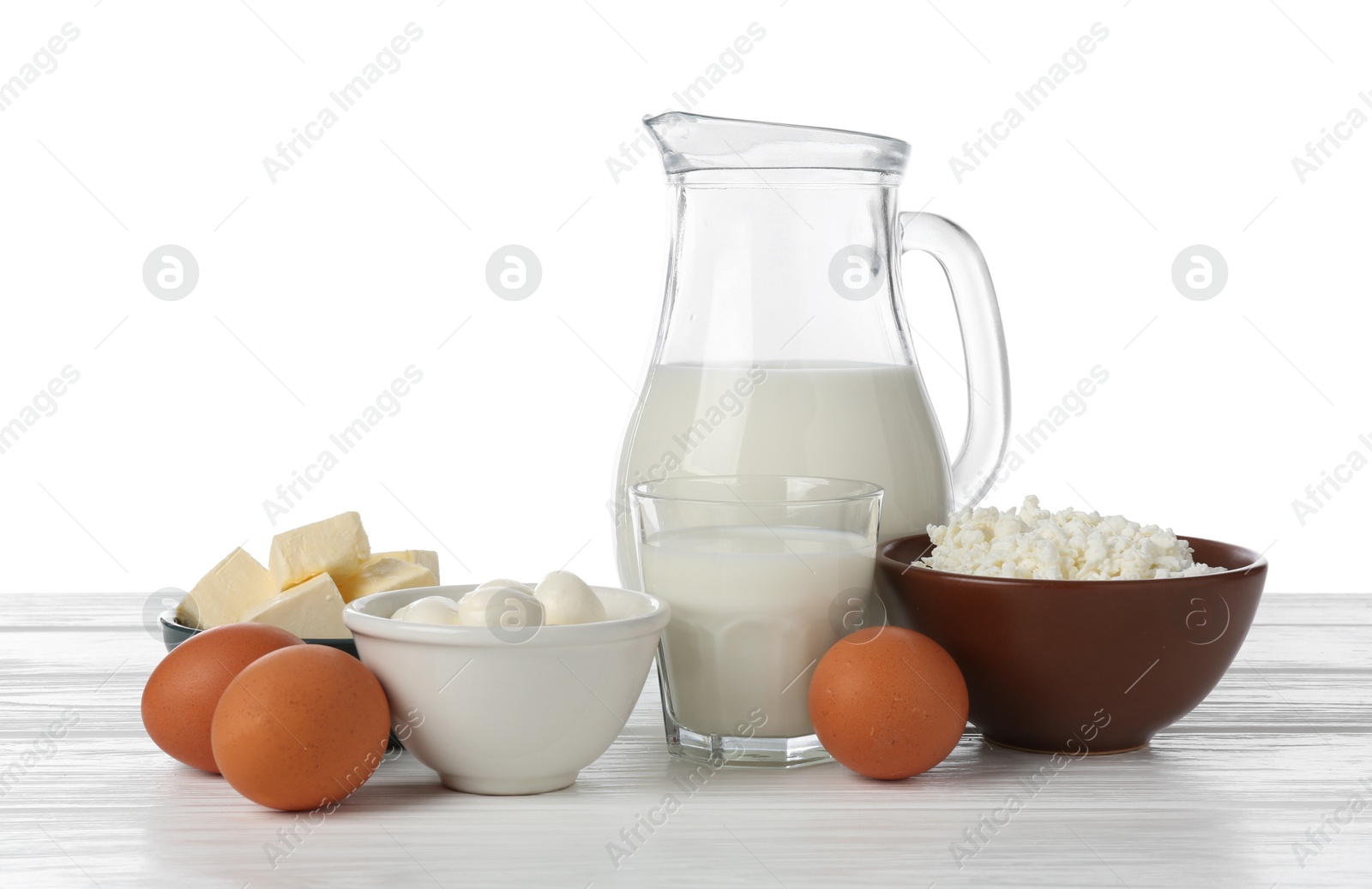 Different dairy products and eggs on wooden table against white background Photo of Different dairy products and eggs on wooden table against white background