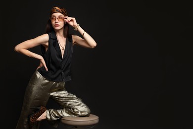 Photo of Beautiful woman in stylish outfit posing on black background, space for text