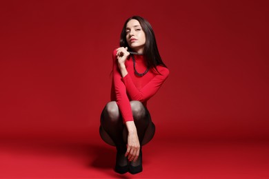 Photo of Full-length portrait of beautiful woman in stylish outfit on red background