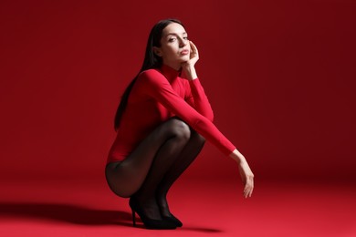 Photo of Full-length portrait of beautiful woman in stylish outfit on red background