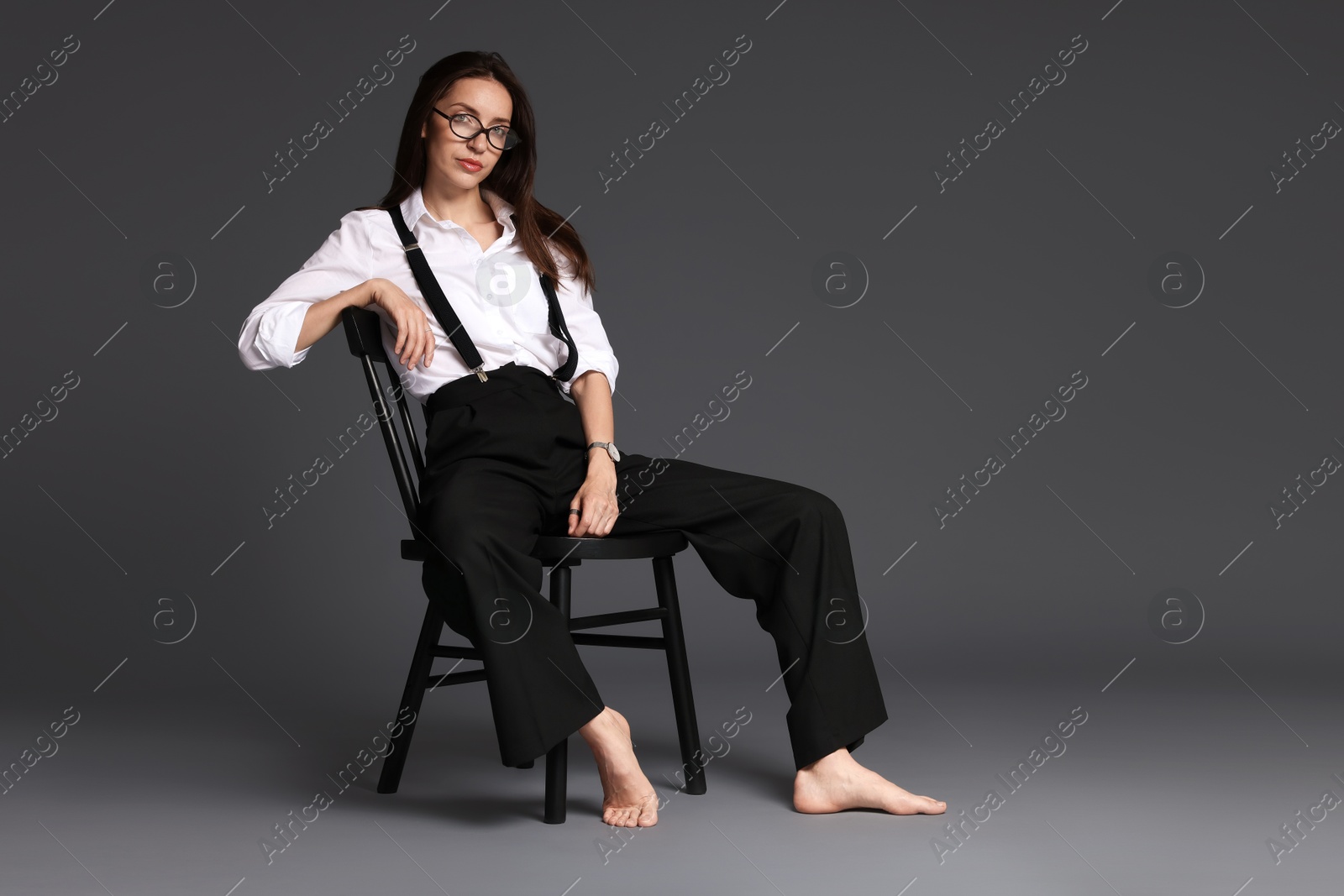 Photo of Beautiful woman in stylish outfit sitting on chair against grey background, space for text