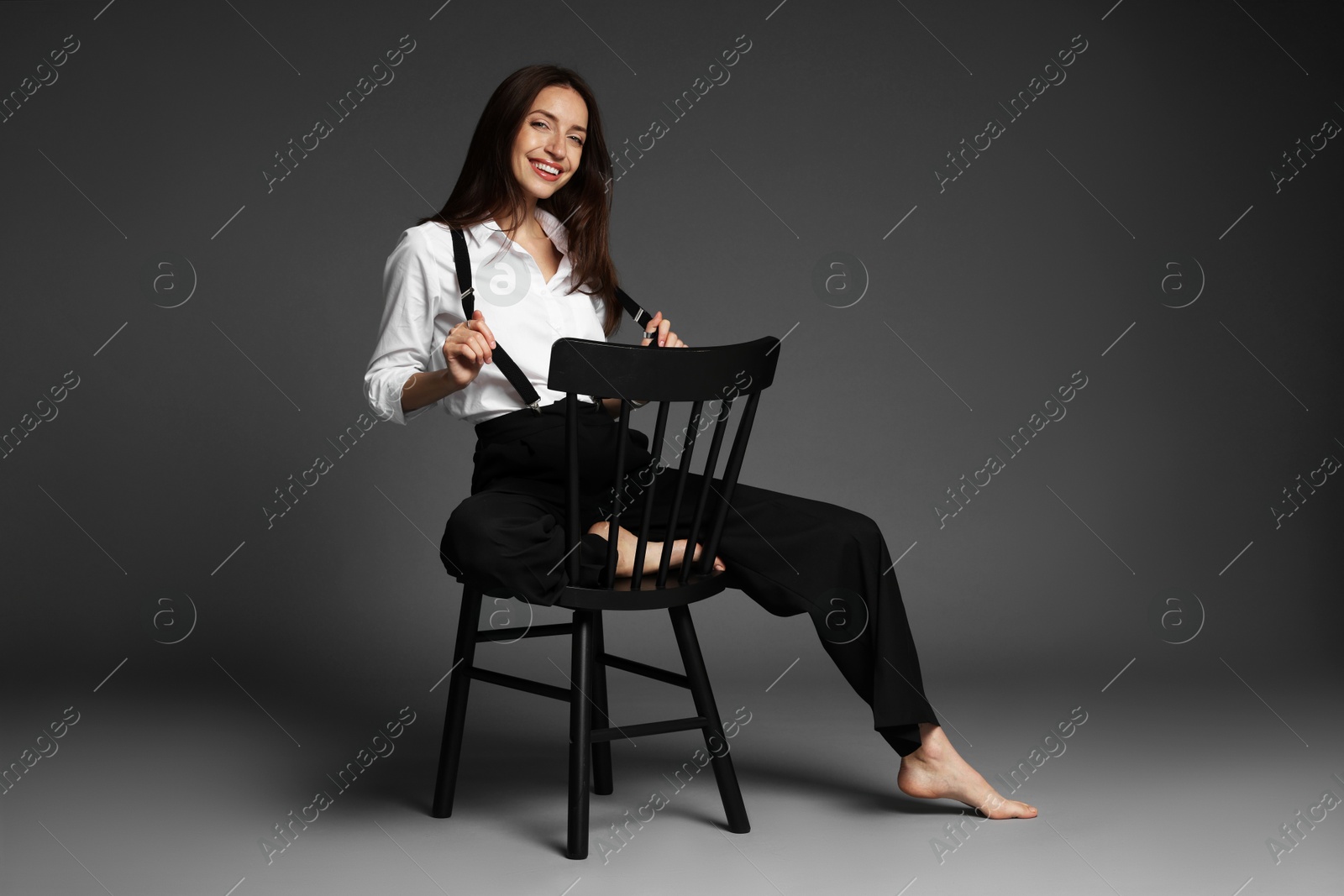 Photo of Beautiful woman in stylish outfit sitting on chair against grey background