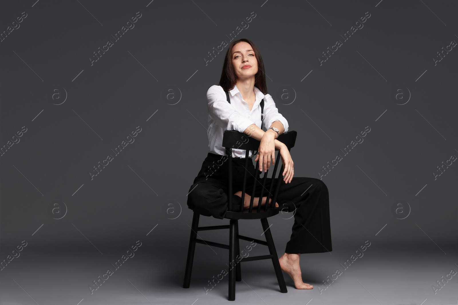 Photo of Beautiful woman in stylish outfit sitting on chair against grey background