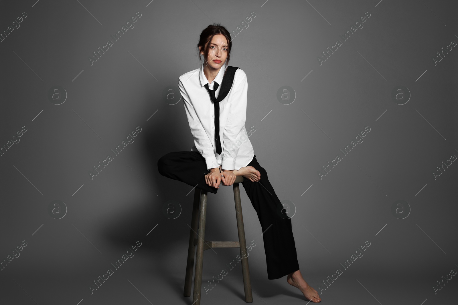 Photo of Beautiful woman in stylish outfit sitting on chair against light grey background