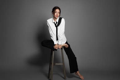 Photo of Beautiful woman in stylish outfit sitting on chair against light grey background