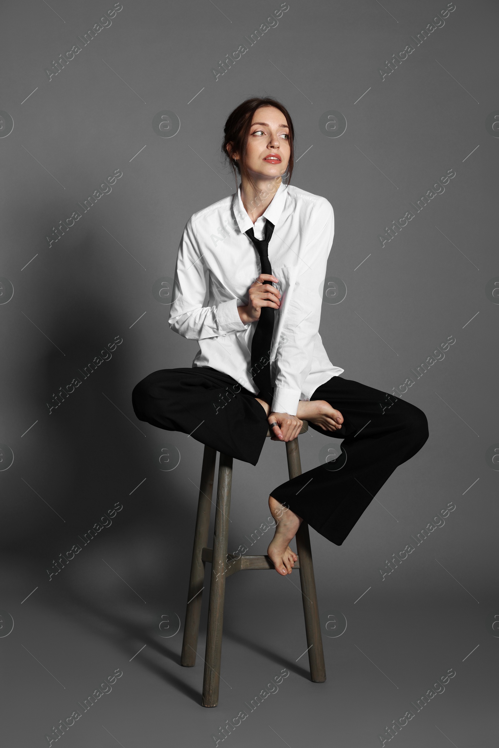 Photo of Beautiful woman in stylish outfit sitting on chair against light grey background
