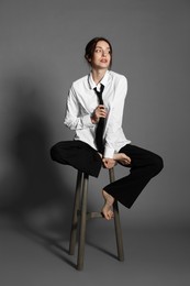 Photo of Beautiful woman in stylish outfit sitting on chair against light grey background