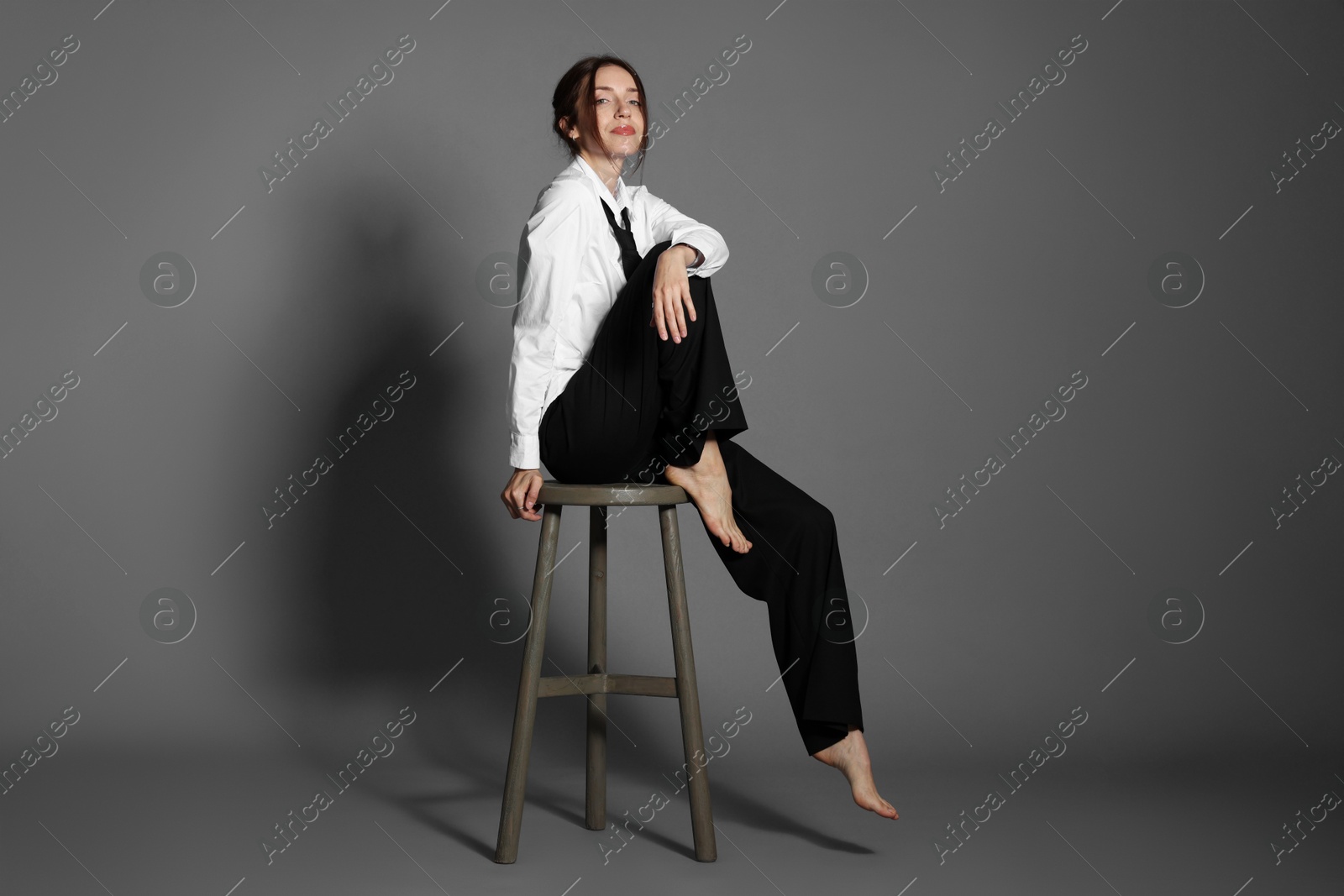 Photo of Beautiful woman in stylish outfit sitting on chair against light grey background