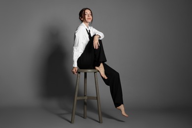 Photo of Beautiful woman in stylish outfit sitting on chair against light grey background