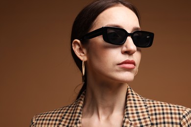 Photo of Portrait of beautiful woman in stylish outfit on brown background