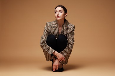 Photo of Full-length portrait of beautiful woman in stylish outfit on beige background