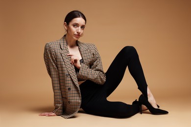 Photo of Full-length portrait of beautiful woman in stylish outfit on beige background