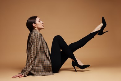 Photo of Full-length portrait of beautiful woman in stylish outfit on beige background